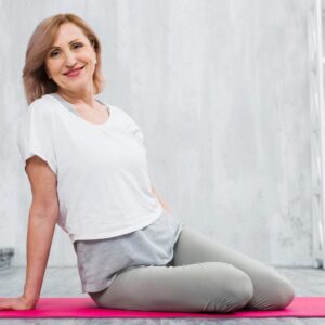 smiling woman sitting on a yoga mat