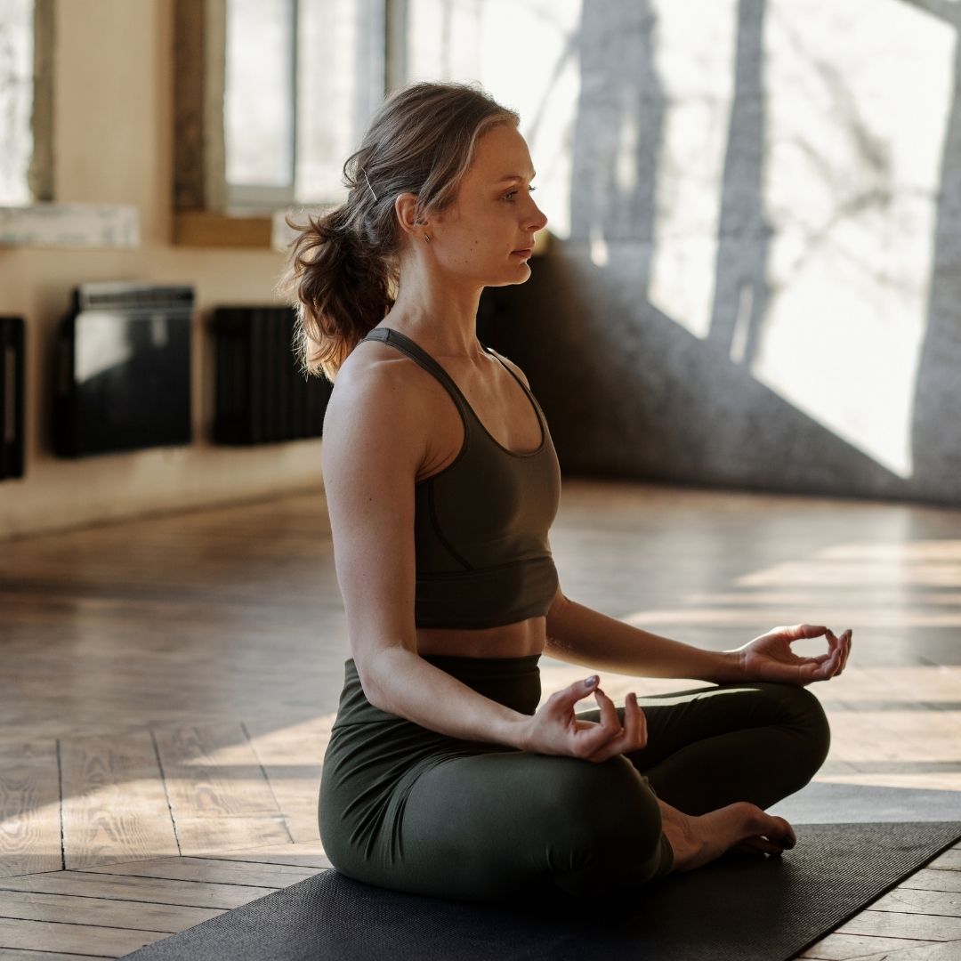 A woman meditating on a yoga mat.